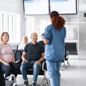A healthcare professional speaks to seated patients in a modern clinic.