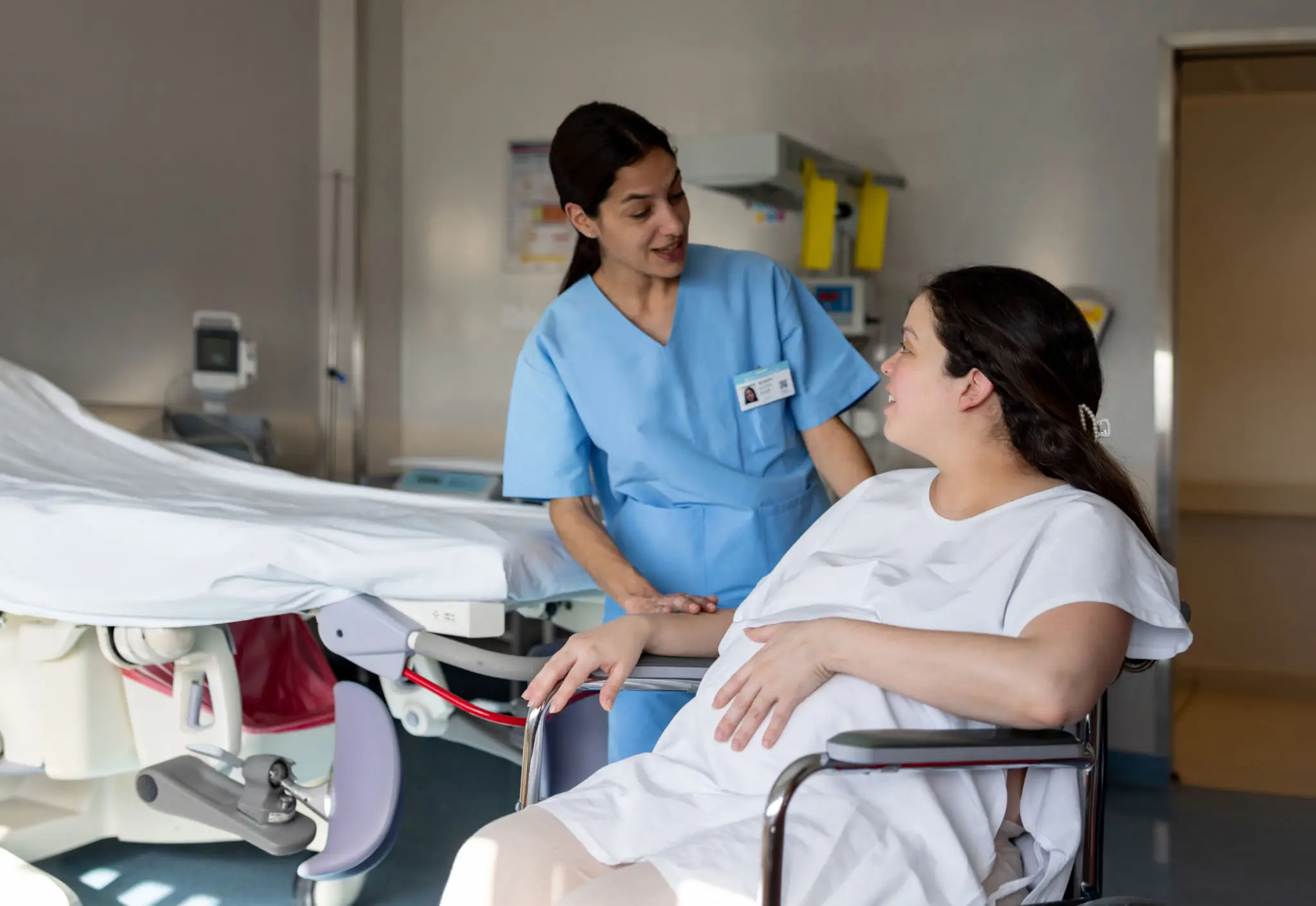 Nurse comforting a pregnant woman in a wheelchair.