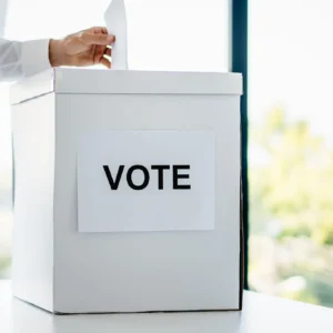 A person casting a vote into a ballot box.