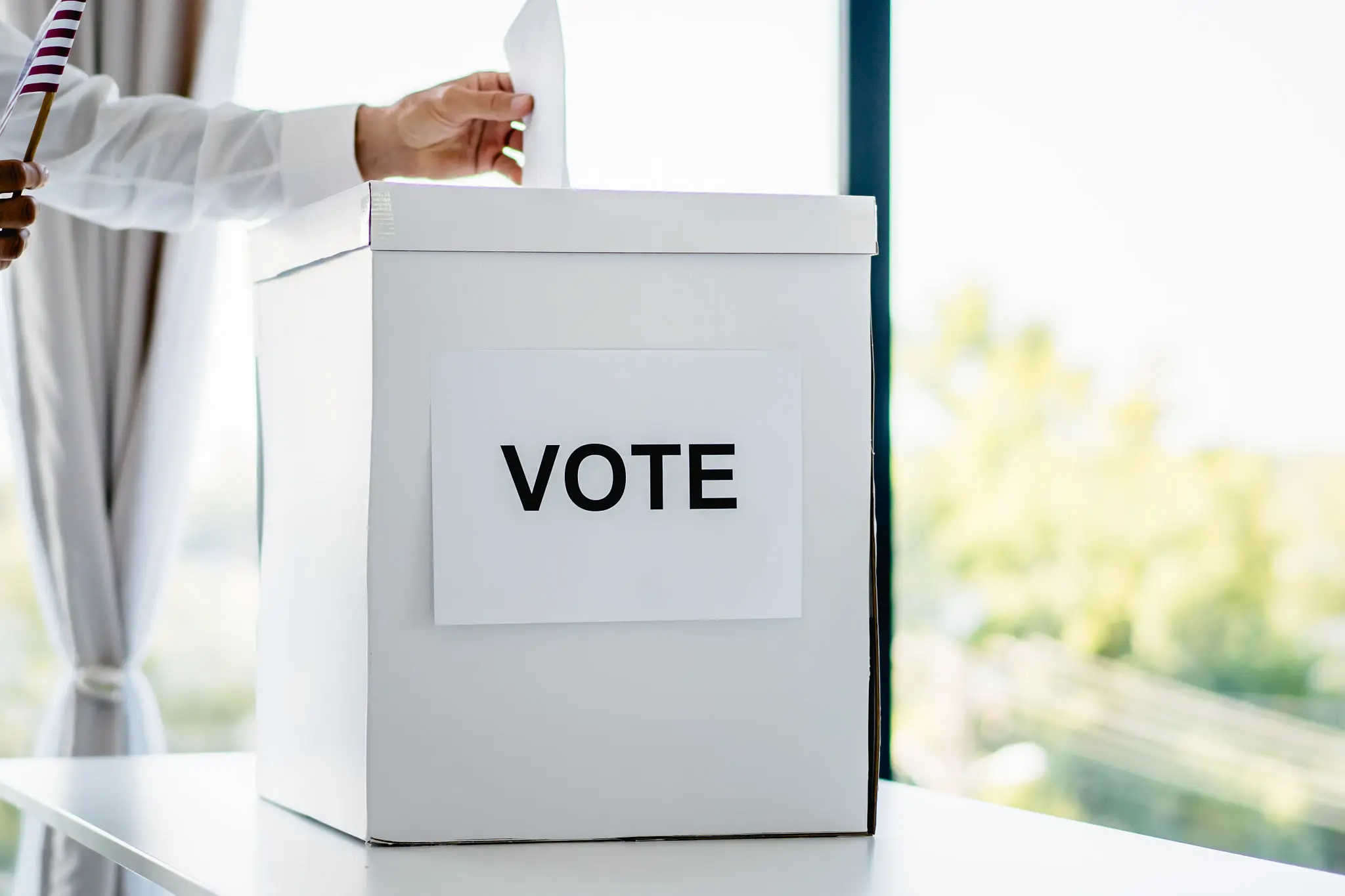 A person casting a vote into a ballot box.