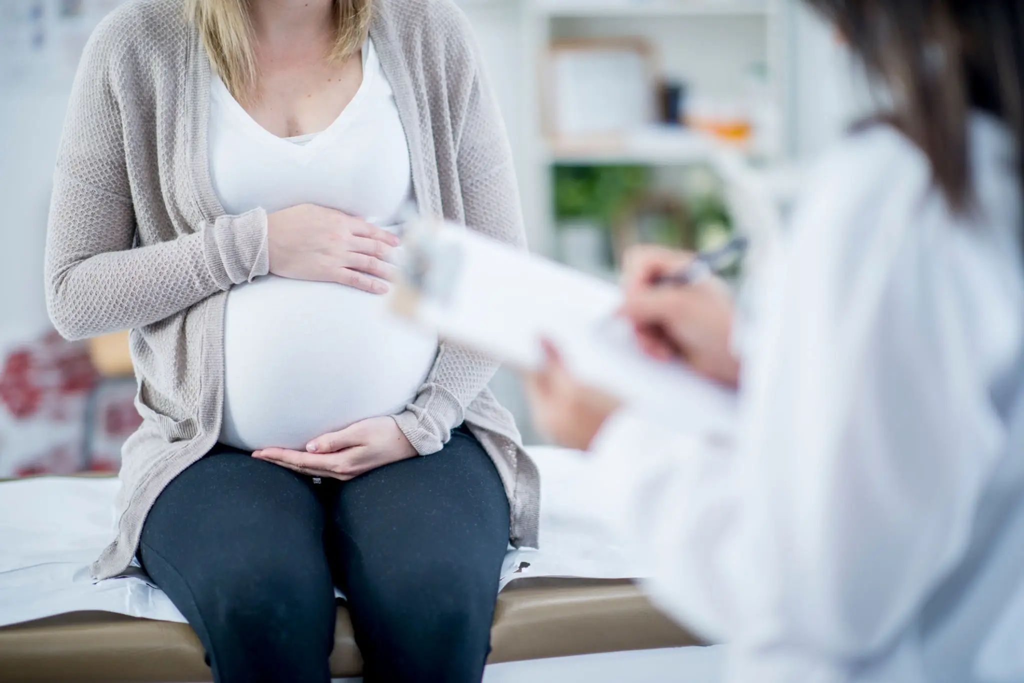 Pregnant woman consulting a doctor in a medical office.